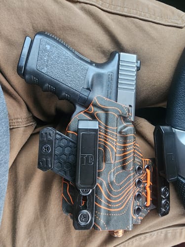 Reviewer's XIPHOS ELITE holster with a black and orange topographic pattern holding a Glock inside the waistband.