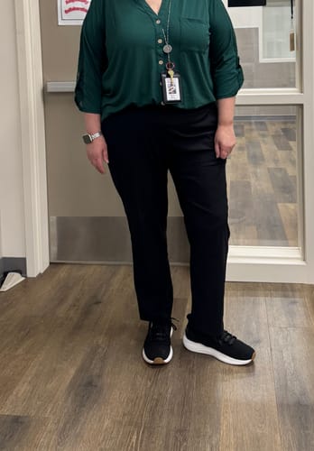 Reviewer standing indoors wearing the black Nicole Ankle Pants, showing how they fit above the ankle on a taller person.