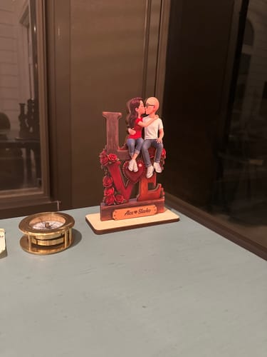 Customer's personalized 'LOVE' wooden plaque showing a couple kissing, displayed on a desk.