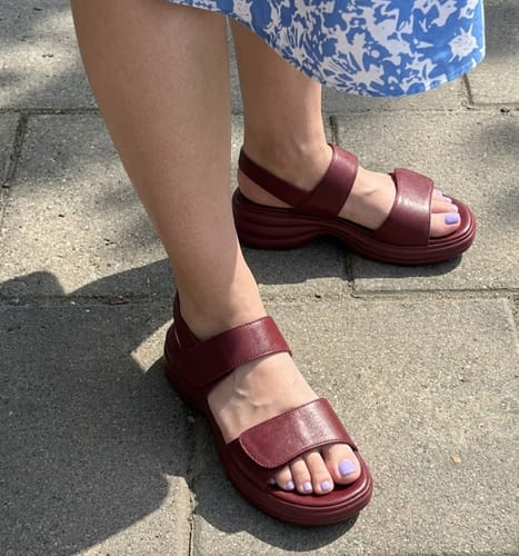 Reviewer wearing the burgundy Modesty sandals, showing the thick straps and contoured sole.