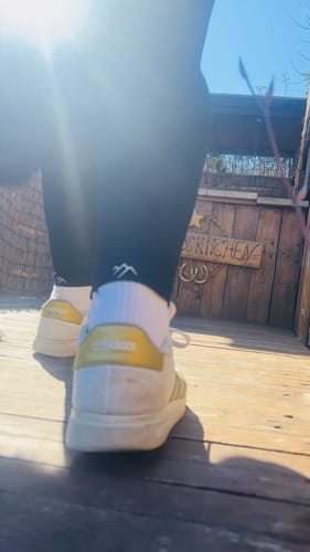 Nahaufnahme der Beine einer Kundin von hinten, die in schwarzen Tofana Leggings geht.