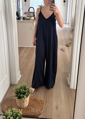 Reviewer wearing the navy Audrey Satin Jumpsuit, showing its loose and wide fit in a mirror selfie.