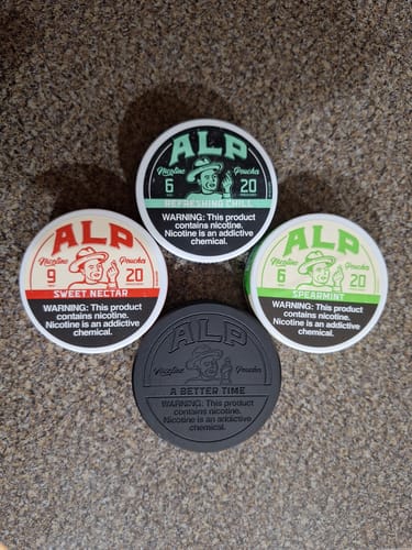 A customer's four tins of ALP nicotine pouches, featuring the Refreshing Chill flavor, laid out on a textured surface.