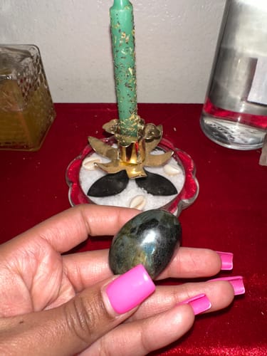 Reviewer's hand holding a dark, polished Labradorite Moonstone from their crystal meditation class.
