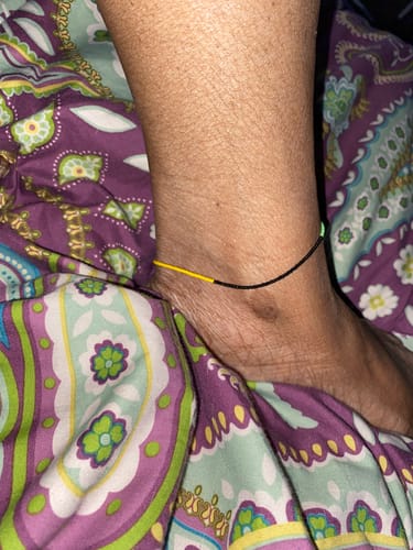Customer showing the Island Anklet with black, yellow, and green beads on their ankle.