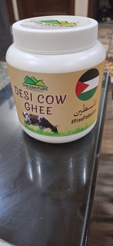 Customer's white jar of Chiltan Pure Desi Cow Ghee sitting on a dark, reflective table.