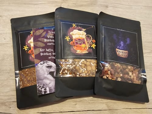Kundenbewertung: Drei schwarze Teebeutel auf einem Holztisch, in der Mitte die Teemischung Butterscotch Brew.