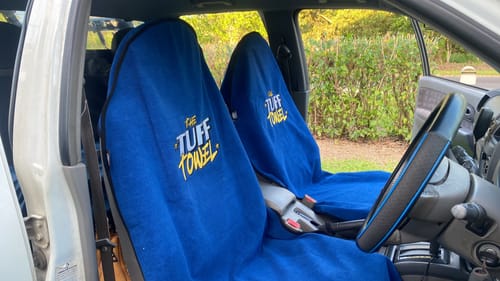 Reviewer's two blue Waterproof Car Towel Seat Covers on the front seats of a car.
