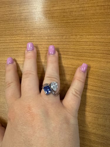 Reviewer's hand wearing the Navae Birthstone Ring with a blue radiant-cut stone and a clear pear-cut stone.