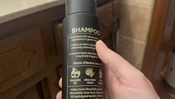 Close-up: Customer's hand holding the black shampoo bottle from the Shower Duo bundle.