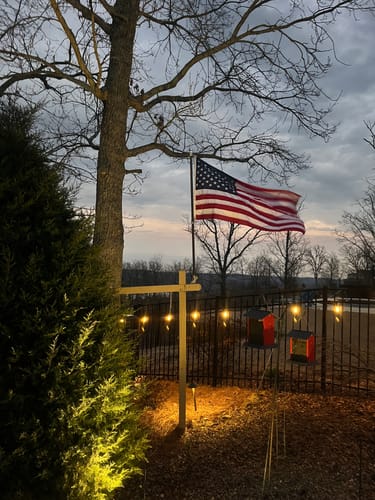 Customer's Prestige House Flag Pole mounted on a yard post, with the American flag waving at dusk.