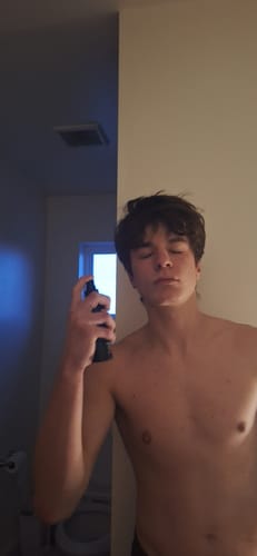 Reviewer with eyes closed applying the Skin Revival Spray to his face and neck.