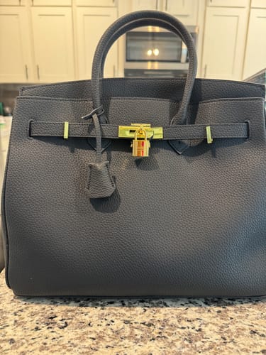 Customer's dark grey pebbled Warkin Bag with gold hardware shown closed on a countertop.