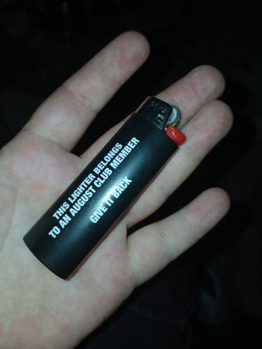 Customer holding the black August Lighter in their palm, showing the white text on the side.