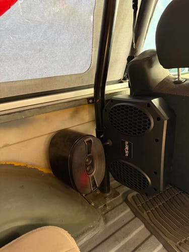 Customer's compact black NSUB installed in the back of a vehicle next to another speaker.