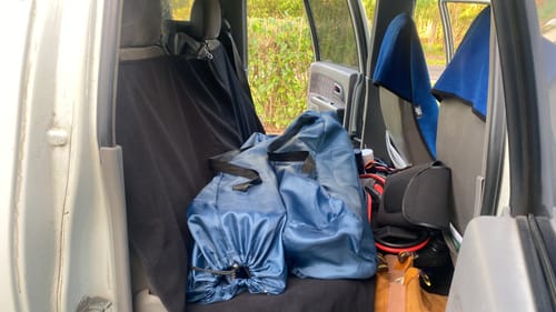 Customer's black Waterproof Backseat Car Towel Seat Cover installed in a vehicle, protecting the seats from blue bags.