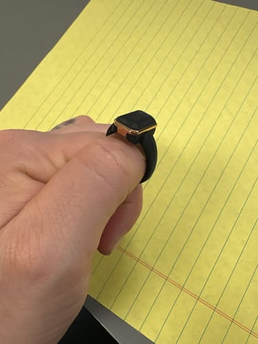 Customer wearing the black Emerald Collection silicone ring with a gold frame on their thumb.