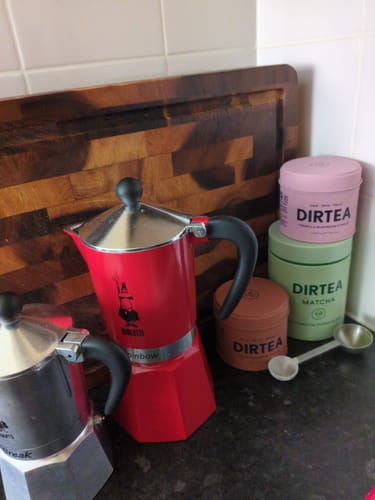 Customer's tins of DIRTEA powders, including the Reishi Mushroom Powder, on a kitchen counter with coffee pots.