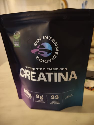 Cliente muestra el empaque negro de la Creatina Monohidrato de Sin Intermediarios sobre una mesa.