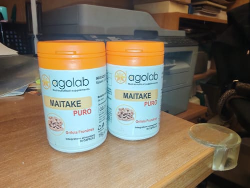 Due flaconi di integratore Maitake Puro del recensore su una scrivania in legno.