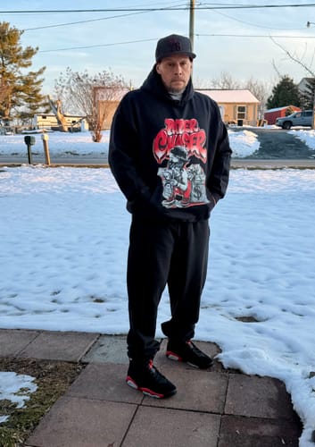 Reviewer wearing the black DopeSkill 'Paper Chaser' graphic hoodie, paired with matching sneakers in a snowy setting.