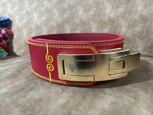 Customer's red Soulgrip Powerkey belt shown from the side with its large gold lever buckle.