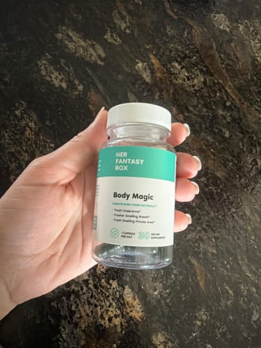 Reviewer holding a bottle of Body Magic Chlorophyll Pills against a dark countertop.