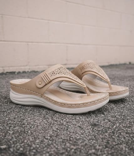 Reviewer's beige Grace sandals shown with their supportive white soles and floral-cutout straps.