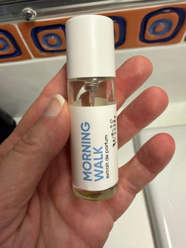Customer holding a small glass bottle of Morning Walk extrait de parfum.