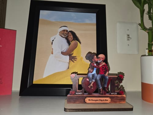 Customer's personalized wooden LOVE plaque with a kissing couple design, displayed on a shelf next to a framed photo.