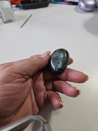 Customer holding a polished, pocket-sized labradorite crystal that shows a flash of color.