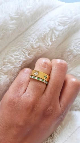 Customer wearing a stacked duo of gold Eloise Birthstone Rings with green and clear stones on their finger.