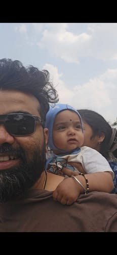 Reviewer wearing the grey-framed Wayfarer Polarized Sunglasses while holding a baby outdoors.