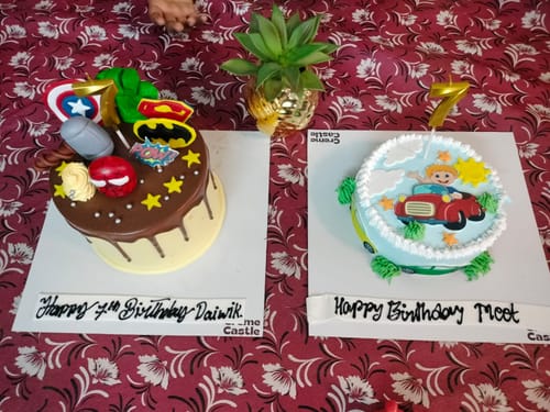 Customer's blue Cars Theme photo cake with a cartoon boy in a car, placed next to another birthday cake.