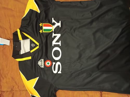 Cliente mostra la maglia retro della Juventus del 1995/96 nera e gialla stesa su una superficie.