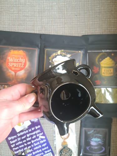 Ein Kunde hält die schwarze Zauberkessel-Duftlampe schräg in der Hand und zeigt die Innenseite.