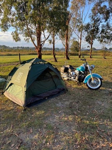 Customer's green 3 Secs Tent set up in a grassy field next to their motorcycle, ready for motocamping.