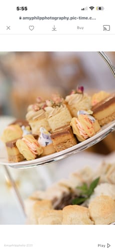 Close-up: Customer's small cakes on a tiered stand decorated with delicate Lilac Violas.