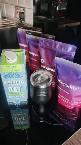 Customer's four bags of rainbow dust on a kitchen counter with pistachio oat milk and a black travel mug.