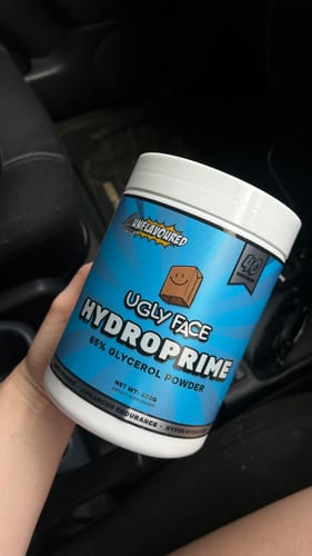 Customer holding a white tub of unflavoured UGLYFACE HYDROPRIME powder inside a car.