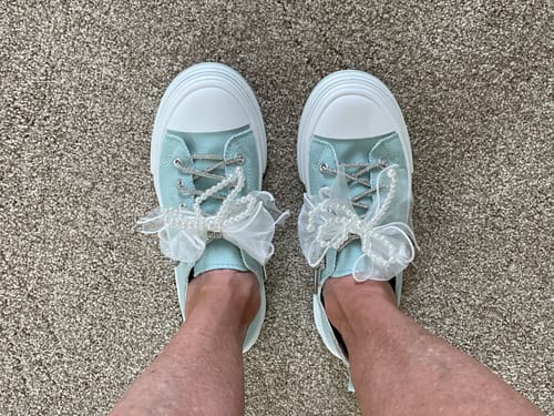 Reviewer's top-down view of their feet in the teal Aman Pearls Sneakers, showing the sheer bows with pearls.