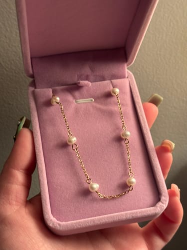 Reviewer holding a pink velvet box with a delicate gold and pearl necklace from the Waterproof Jewelry Bundle.
