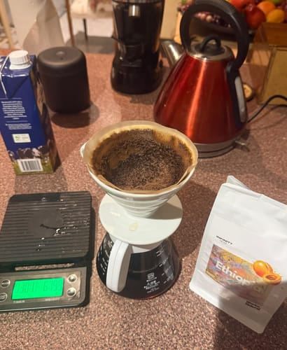 Reviewer making pour-over coffee on a counter with the bag of Ethiopian coffee from their subscription.