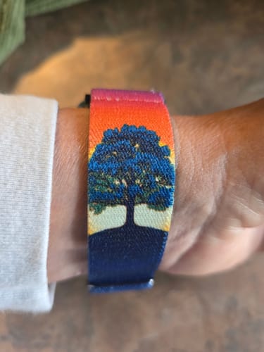 Customer's Rooted In Peace Watch Band on their wrist, showing the detailed tree design against a colorful background.