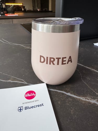 Customer's pink DIRTEA mug sitting on a dark kitchen counter.