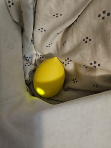 Customer's yellow Lem Clitoral Massager resting in patterned fabric.