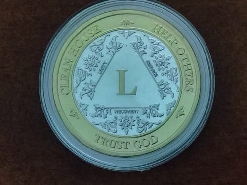 Customer's bi-plate 50-year AA Medallion in its protective capsule, showing the front design with the Roman numeral L.