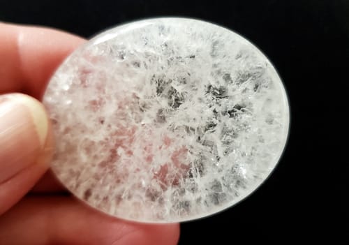 Reviewer holding the polished clear quartz worry stone, showing its detailed internal structure.