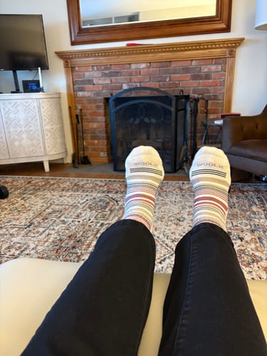 Customer relaxing with their feet up, wearing the striped Womens Everyday Crew Socks indoors.