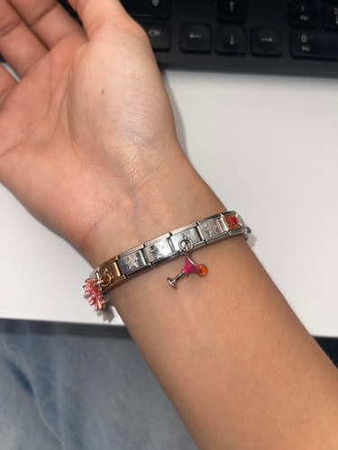 Una clienta muestra su pulsera con el Charm Coctel rosa colgando.